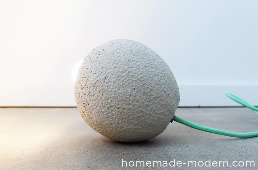 I've always like the texture of cantaloupes, so I made this concrete lamp by creating a silicone mold with a real cantaloupe and then casting a hollow concrete version. I used a plastic water bottle and a threaded rod to make the chase and hollow part of the lamp and a cloth cord from ColorCord.com to wire the lamp. For more information go to HomeMade-Modern.com.